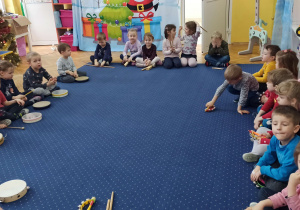 Dzieci siedzą na dywanie z instrumentami muzycznymi